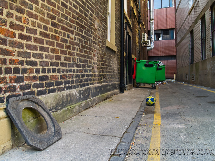 bins 
 Back street football and bins 
 Keywords: urban city town concrete brick alley bin rubbish football